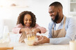 © Prostock-studio - Happy family mixing dough together in modern kitchen