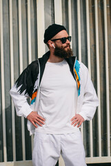 Wall Mural - Young bearded hipster guy wearing a vintage tracksuit and white blank t-shirt. Mock-up for print. T-shirt template.