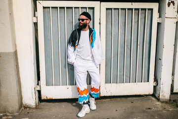 Wall Mural - Young bearded hipster guy wearing a vintage tracksuit and white blank t-shirt. Mock-up for print. T-shirt template.