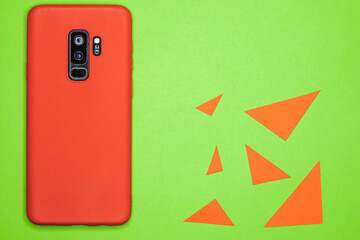 Canvas Print - Top view of a red mobile phone on a green surface surrounded by triangles