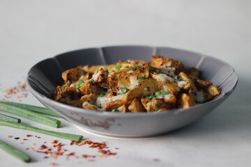 Wall Mural - Cheesy potato wedges made by baking air fried potato wedges after sprinkling it with shredded mozzarella, chilli flakes and chopped green onions.