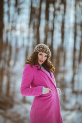 Wall Mural - Shallow focus shot of a beautiful Caucasian woman posing in the snowy forest