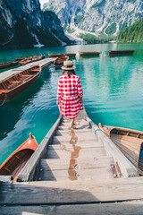 Wall Mural - young gentle woman in red checkered dress barefoot walking by wooden stairs of boat station leads to lake