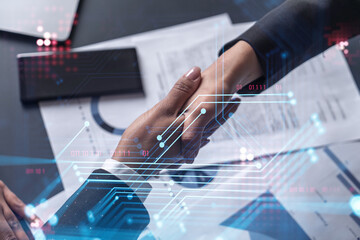 Handshake of two businesswomen who enters into the contract to develop a new software to improve business service at a company. Technological icons over the table with the document.