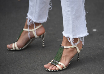 Wall Mural - Detail of a fashionable outfit –woman wearing white pants and white sandals with metal details