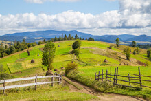 Wooden Fence Near The Road On A Background Of Mountains On The Fields. Countryside.