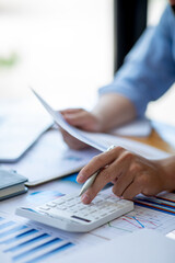 Close up of Business using calculator and laptop for doing math finance report on wooden desk, tax, accounting, statistics and analytical research concept