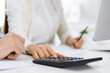 © Iryna - Bookkeeper checking balance with calculator or making finance report, close-up of hands. Tax and audit concepts