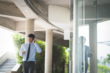 Wall Mural - Attractive asian business man using mobile phone while walking in office building.