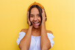 © Asier - Young mixed race woman isolated on yellow background laughs joyfully keeping hands on head. Happiness concept.