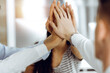 © Iryna - Group of business people joining hands or giving five to each other after meeting or negotiation in sunny office