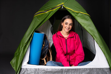 young caucasian woman inside a camping green tent laughing
