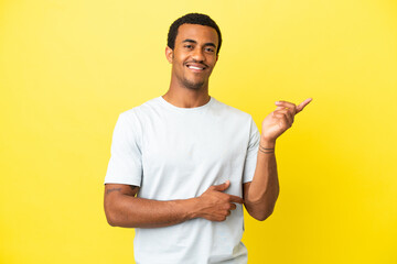 Wall Mural - African American handsome man on isolated yellow background happy and pointing up