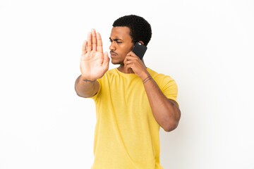 Wall Mural - African American handsome man using mobile phone over isolated white background making stop gesture and disappointed