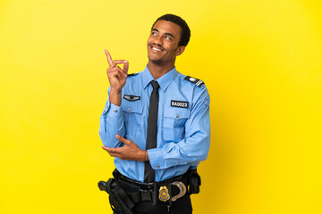 Wall Mural - African American police man over isolated yellow background pointing up a great idea