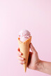 Female hand holding the ice cream, pink background