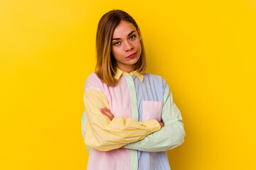 Young caucasian skinny woman isolated on yellow background suspicious, uncertain, examining you.