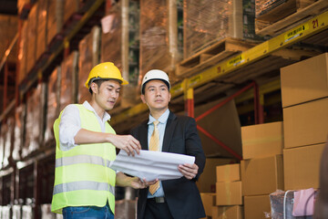 Young Asian man owner manager stand to talk with worker near shelf product box in warehouse factory store which smile and felling happy, logistic import and export transportation concept