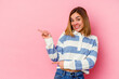 © Asier - Young caucasian woman isolated on pink background excited pointing with forefingers away.