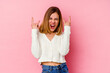 © Asier - Young caucasian woman isolated on pink background showing a horns gesture as a revolution concept.