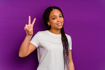 Young african american woman isolated on yellow background joyful and carefree showing a peace symbol with fingers.