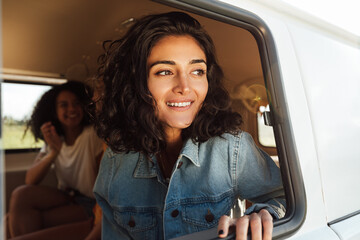 Beautiful brunette woman sitting in camper van looking out of window