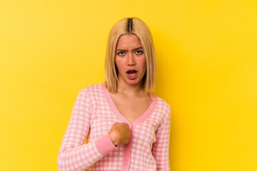 Poster - Young venezuelan woman isolated on yellow background surprised pointing with finger, smiling broadly.