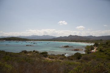 Sticker - Aerial view of a seascape with swimming people surrounded by trees and mountains under a cloudy sky