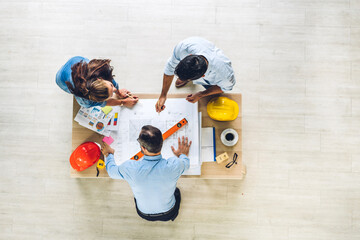 Wall Mural - Top view of professional of team engineer cargo foreman in helmets working with blueprint and construction tool on table at the construction site