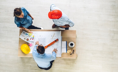 Wall Mural - Top view of professional of team engineer cargo foreman in helmets working with blueprint and construction tool on table at the construction site