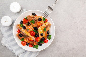 Wall Mural - Baked perch fish fillets, italian style in crazy water with black olives, tomatoes and capers, with fresh parsley. Top view.