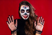 Mexican Young Woman In A Costume Of Calavera Catrina Over Red Studio Background