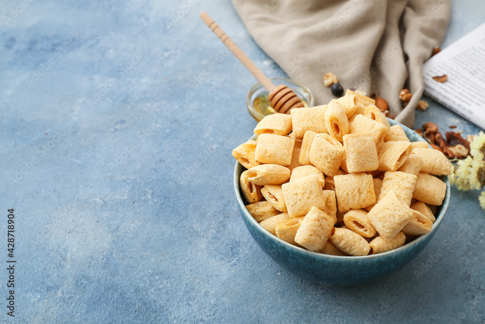 Bowl with tasty corn pillows on color background