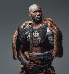 Wall Mural - Bearded black skinned barbarian with fur and shaved head holding an axe