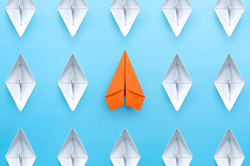 Wall Mural - Orange paper plane standing out from the group of white paper boats, Business concept for new ideas creativity and innovative solution