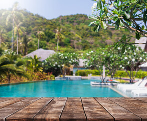 Empty wood table top and blurred swimming pool in tropical resort in summer banner background - can used for display or montage your products.