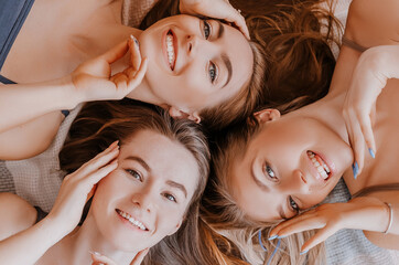 Wall Mural - women rest and have fun. girlfriends laugh at home lying on the floor on pillows. tree girls make ho