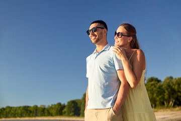 Poster - leisure, relationships and people concept - happy couple in sunglasses hugging on summer beach