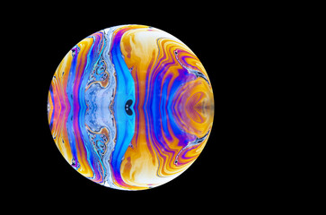 close up of a soap bubble. Close up of a abstract, soap bubble resembling a planet. Copy space on a black background.