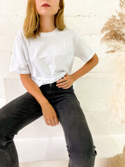 Wall Mural - Beautiful young woman in blank white t-shirt and black jeans sitting on the stairs