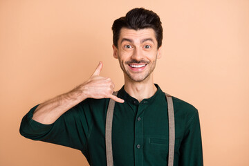 Wall Mural - Photo of promoter guy fingers phone ask call beaming smile wear green shirt suspenders isolated beige background