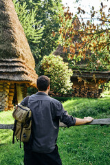 Wall Mural - A man with a backpack walks through the countryside and enjoys the beautiful ethnic architecture. Outdoor adventure. Rest in the country. Travel and exploration. Healthy lifestyle