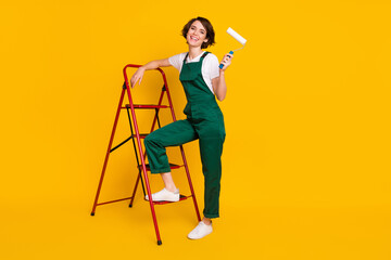 Sticker - Full size photo of happy excited positive good mood woman painter with ladder hold roller isolated on yellow color background