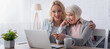 © LIGHTFIELD STUDIOS - Cheerful woman pointing with finger at laptop near tea and daughter, banner