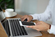 © Tarokmew - Young businessman hand holding smartphone and checking and replying to emails in the laptop on office desk.
