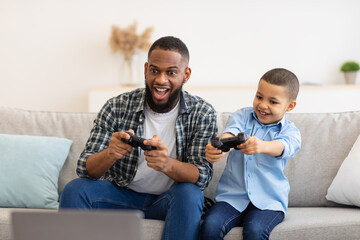 Excited African Daddy And Son Boy Playing Game At Home