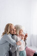© LIGHTFIELD STUDIOS - Adult woman with closed eyes embracing senior mother in living room