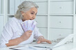 © aletia2011 - Senior doctor sitting at table with laptop and holding money
