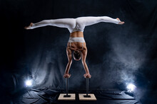 Flexible Circus Artist - Female Acrobat Doing Handstand On The Back And Smoker Background