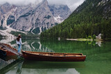 Fototapeta Sypialnia - Woman traveler in a hat standing at the bank of beautiful lake